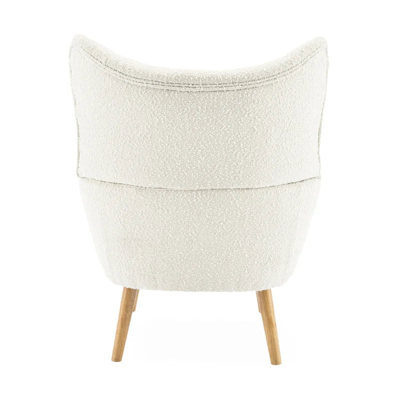 Poltrona club wingback trapuntata in bouclé con gambe in legno di hevea